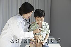 Asia Images Group - Doctor listening to young boy's heart.