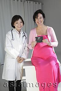 Asia Images Group - Female doctor with pregnant woman holding sonogram
