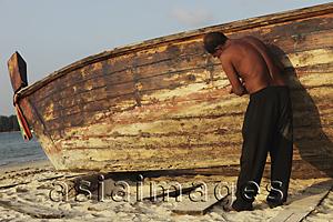 Asia Images Group - Asian man fixing boat on the beach