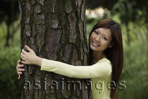 Asia Images Group - Chinese woman hugging a tree and smiling