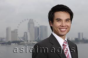 Asia Images Group - Chinese man in suit standing in front of city skyline, smiling