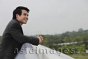 Asia Images Group - Man wearing suit leaning on wall and looking at view