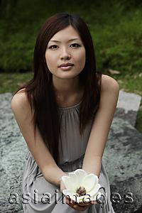 Asia Images Group - Young woman holding white flower and looking at camera