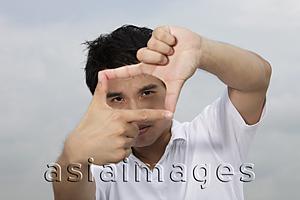 Asia Images Group - Asian man looking through finger frame