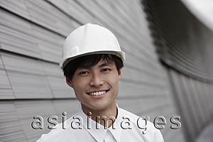 Asia Images Group - man wearing construction hat smiling in front of building