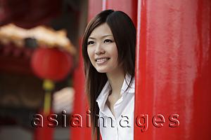 Asia Images Group - Chinese woman looking out from behind red pillars