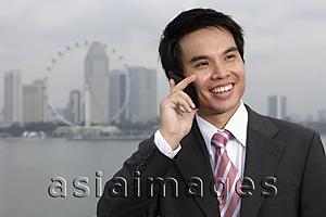 Asia Images Group - Chinese business man talking on phone in front of city skyline