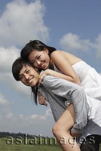 Asia Images Group - young man carrying a woman on his back outside