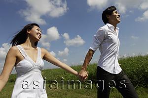Asia Images Group - young couple holding hands and smiling outside