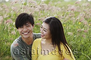Asia Images Group - young couple sitting in field together laughing