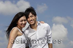 Asia Images Group - young couple smiling together with blue sky and clouds as background