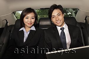 Asia Images Group - man and woman wearing business suits in back seat of car