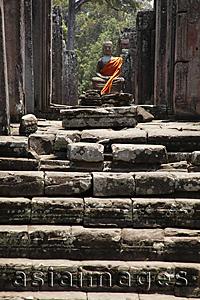 Asia Images Group - Stone carving of Buddha wrapped in orange robe. Angkor Wat, Cambodia