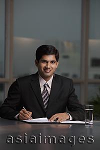 Asia Images Group - Indian man sitting at table writing