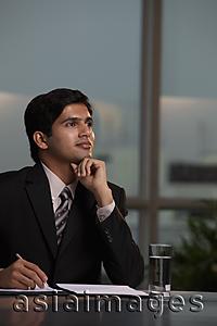 Asia Images Group - Indian man sitting at desk thinking and writing