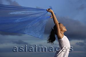 Asia Images Group - young girl holding up blue cloth, blue sky background
