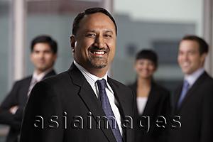 Asia Images Group - Indian man smiling at camera with colleagues behind him