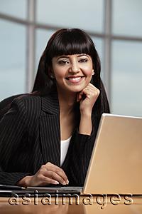 Asia Images Group - Indian woman smiling while working on laptop