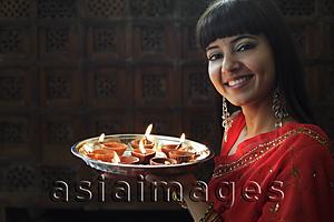 Asia Images Group - Indian woman holding tray of lit oil lamps