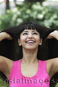 Asia Images Group - Head shot of woman looking up and smiling with hands in her hair