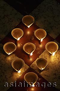 Asia Images Group - Lit oil lamps in a triangle shape on floor