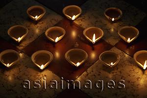 Asia Images Group - A group of lit clay oil lamps on floor