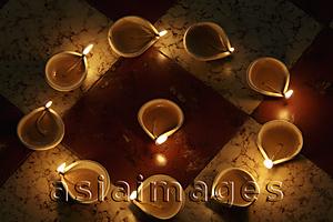 Asia Images Group - Lit clay oil lamps in a circle