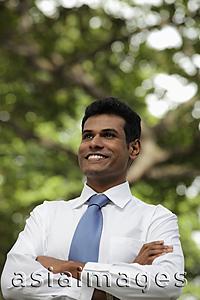 Asia Images Group - Indian man looking up and smiling with folded arms
