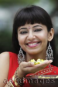 Asia Images Group - Head shot of Indian woman smiling and holding flowers