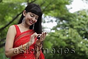 Asia Images Group - Indian woman texting on phone, outdoors