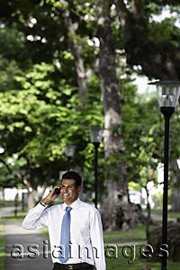 Asia Images Group - Indian man talking on phone under trees
