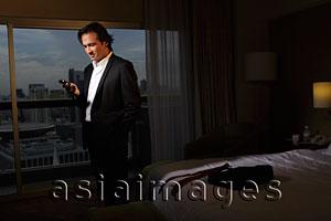 Asia Images Group - man wearing suit in hotel room looking at phone