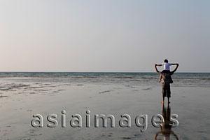 Asia Images Group - Boy sitting on father's shoulders and holding hands and looking at the ocean