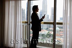 Asia Images Group - Man wearing suit holding phone looking out window