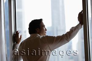 Asia Images Group - Profile of man looking out of window at city