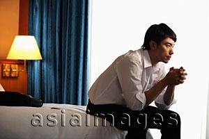Asia Images Group - Profile of man sitting on the bed in hotel room