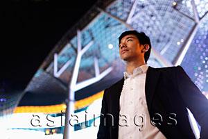 Asia Images Group - young man in suit standing in front of building at night