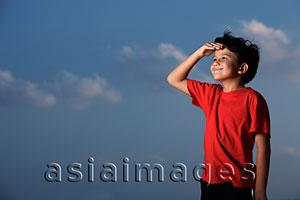 Asia Images Group - Young boy wearing a red shirt looking out with hand shielding eyes