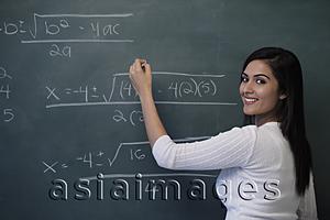 Asia Images Group - Young woman writing math equation on chalk board and smiling