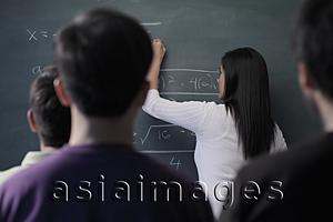 Asia Images Group - Rear view of students watching teacher write on chalk board
