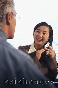 Asia Images Group - Female executive holding telephone talking with Caucasian male executive