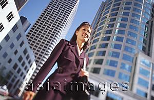 Asia Images Group - Female executive standing in front of office buildings, low angle view