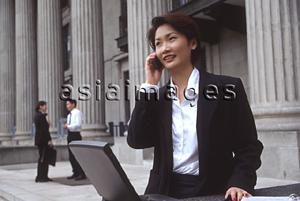 Asia Images Group - Female executive with laptop computer and cellular phone