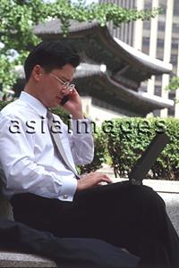 Asia Images Group - Male executive with laptop computer and cellular phone in Seoul, Korea
