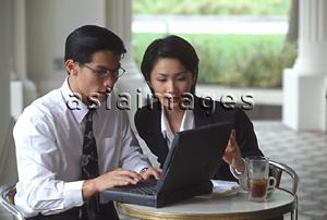 Asia Images Group - Male and female executives working on laptop computer in cafe