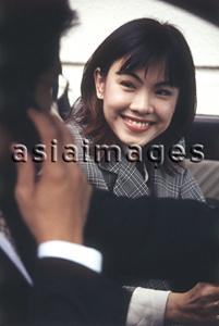 Asia Images Group - Female executive smiling at male executive talking on cellular phone in car