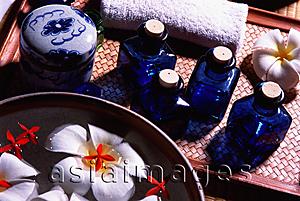 Asia Images Group - Blue glass bottles beside a bowl with floating fresh flowers