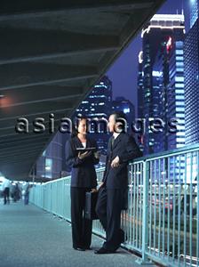 Asia Images Group - Two executives talking at night, skyline behind