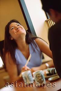 Asia Images Group - Young couple dining in restaurant, woman holding chopsticks laughing