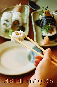 Asia Images Group - Hand holding chopsticks picking up sushi